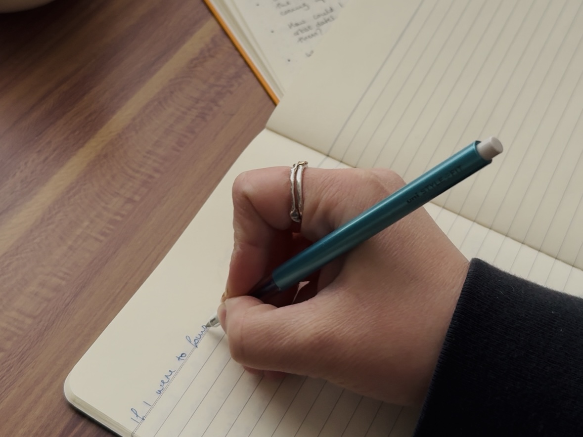 Hand holding a pen writing in a notebook
